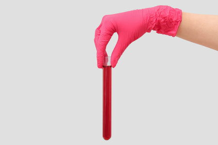 Lab's worker hand with test tube of sample on gray background