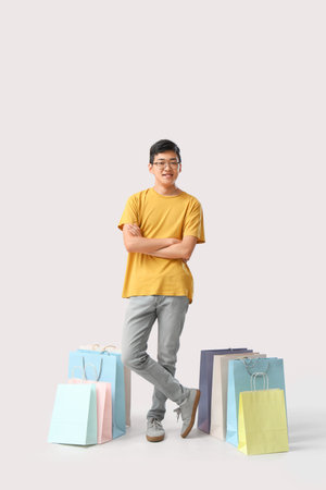 Young Asian man with shopping bags on white backgroundの写真素材