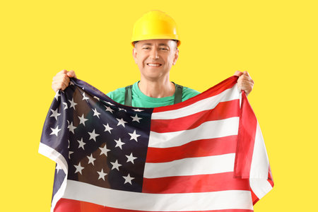 Mature worker with USA flag on yellow background. labor day celebrationの写真素材