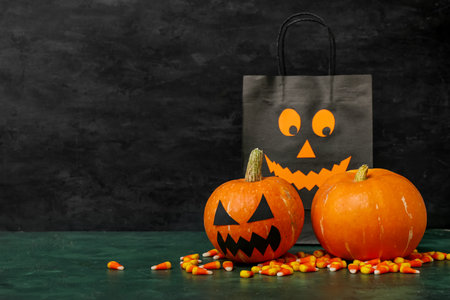 Pumpkins for Halloween celebration, shopping bag and tasty candy corns on color backgroundの写真素材