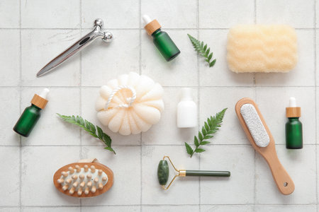 Face massage rollers and bathing supplies on light tile backgroundの写真素材