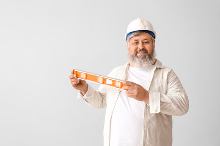 Portrait of senior man in hardhat with level on gray background. labor day celebrationの写真素材