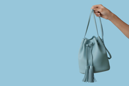 Female hand with stylish blue bag on color backgroundの写真素材
