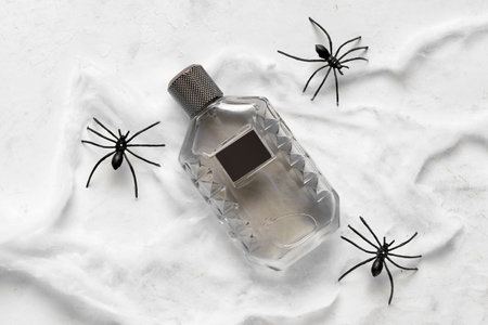 Bottle of elegant perfume with spiderweb for Halloween celebration on grunge white backgroundの写真素材