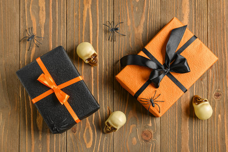 Gift boxes with spiders and skulls for Halloween celebration on brown wooden backgroundの写真素材