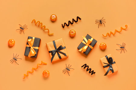 Gift boxes with Halloween decorations on orange backgroundの写真素材