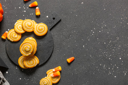 Plate with tasty Halloween cookies and candy corns on grunge black backgroundの写真素材