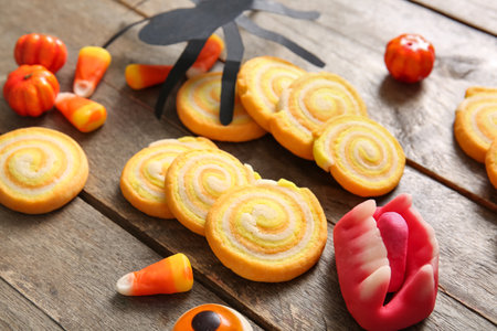 Tasty cookies with candies and paper spider for Halloween celebration on brown wooden backgroundの写真素材