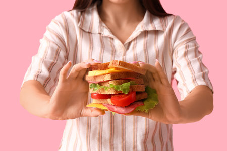 Young woman with tasty sandwich on pink background, closeupの写真素材