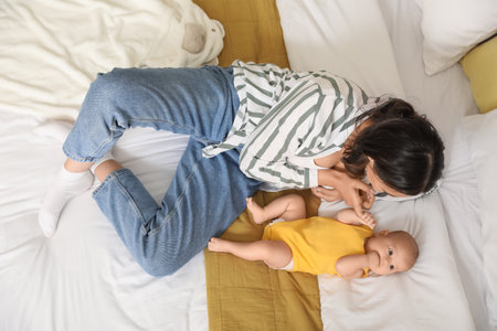 Young woman with her baby lying on bed, top viewの写真素材