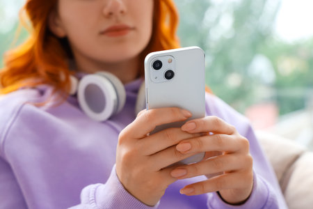 Young woman using mobile phone at home, closeupの写真素材