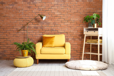 Stylish yellow armchair and pouf with houseplant in interior of living roomの写真素材