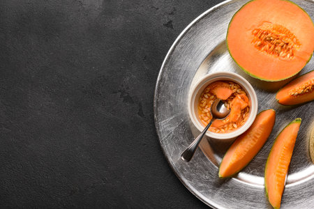 Plate with ripe cut melon on black background