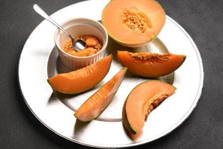 Plate with ripe cut melon on black backgroundの写真素材