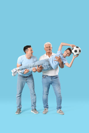 Little boy with his dad and grandfather holding soccer ball on blue backgroundの写真素材