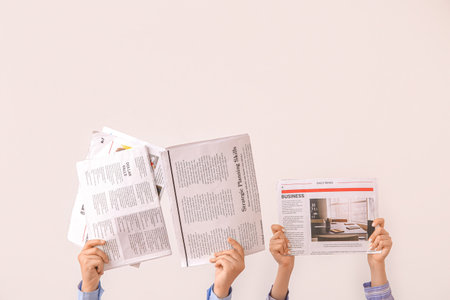 Female hands with different newspapers on light backgroundの写真素材