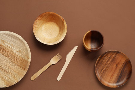 Different wooden tableware on brown background