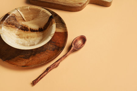 Wooden plate, bowl and spoon on beige background, closeupの写真素材