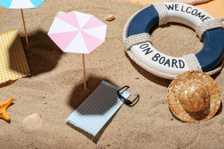 Creative summer composition with mini umbrellas, beach accessories and sand on beige background