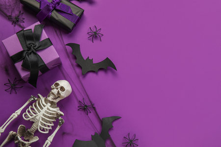 Composition with gift boxes, skeleton and Halloween decor on purple backgroundの写真素材