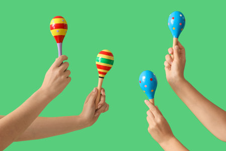 Female hands holding maracas on green background