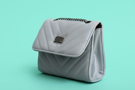 Stylish blue chain bag on turquoise background