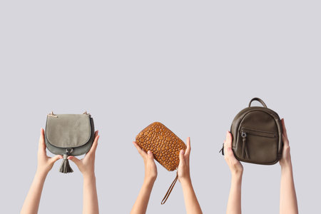 Female hands holding different stylish bags on gray backgroundの写真素材