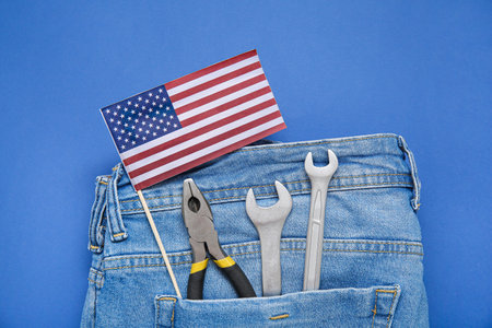 Jeans with different tools and USA flag in pocket on blue background. Labor Day celebrationの写真素材
