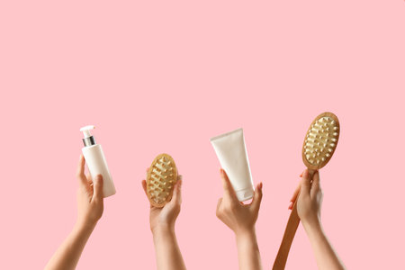 Female hands holding cosmetic products on pink backgroundの写真素材
