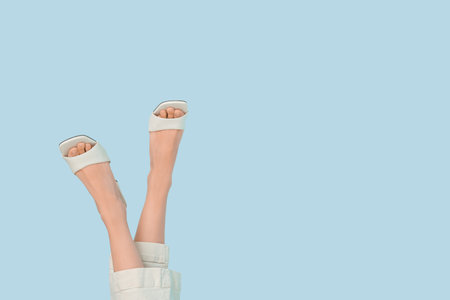 Woman in stylish sandals on color background