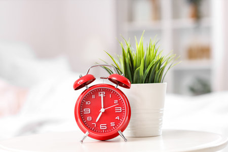 Alarm clock and houseplant on table in bedroom, closeupの写真素材