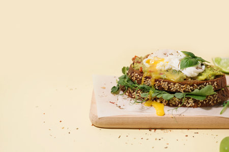 Wooden board of tasty sandwich with egg on yellow backgroundの写真素材