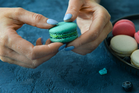 Woman holding sweet macaroon on blue backgroundの写真素材