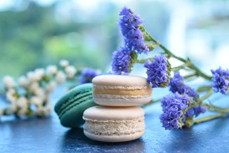 Sweet macaroons and beautiful flowers on blue table