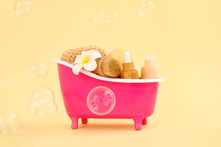 Small bathtub with different bath supplies and soap bubbles on color background