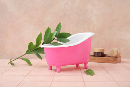 Small bathtub, bath supplies and plant branch on color tile tableの写真素材