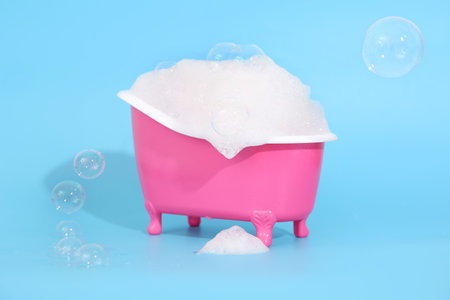 Small bathtub with fluffy soap foam on color backgroundの写真素材