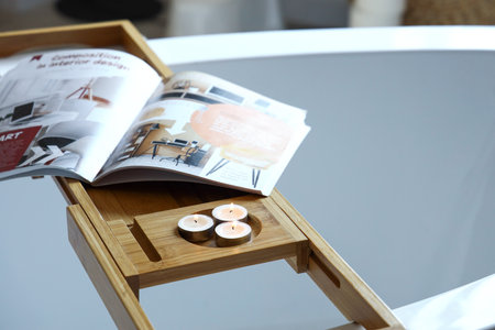 Wooden bathtub tray with burning candles and magazine in bathroom, closeupの写真素材