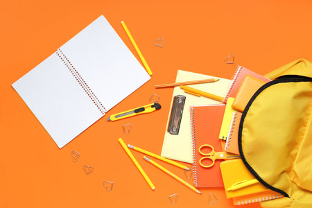 Stylish school backpack and different stationery on orange backgroundの写真素材