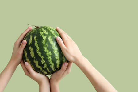 Female hands with watermelon on green backgroundの写真素材
