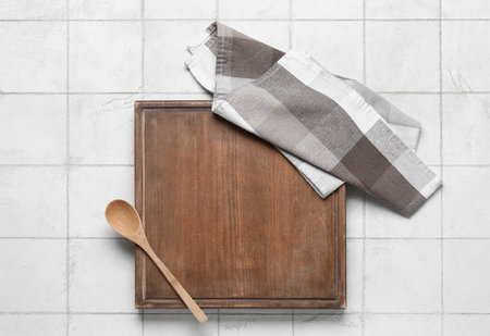 Wooden board with spoon and napkin on white tile kitchen tableの写真素材