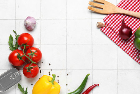 Napkin with spoon and fresh vegetables on white tile kitchen tableの写真素材