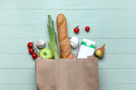 Paper bag full of fresh products on green wooden backgroundの写真素材