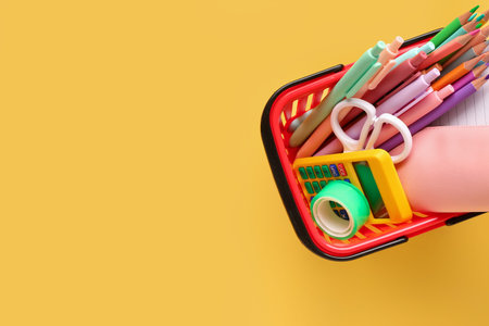 Shopping basket with different stationery on color background