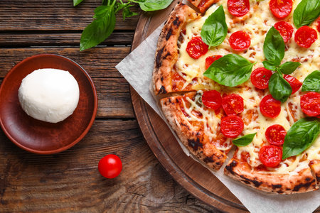 Board with tasty pizza Margarita and Mozzarella cheese on wooden backgroundの写真素材