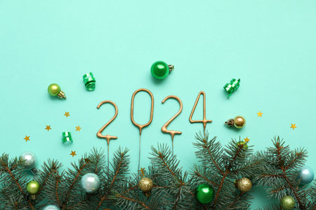 Figure 2024 made of sparklers with Christmas decorations and fir branches on turquoise backgroundの写真素材