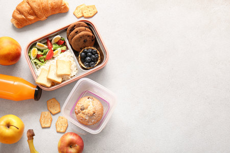 Lunchboxes with delicious food and bottle of juice on light backgroundの写真素材