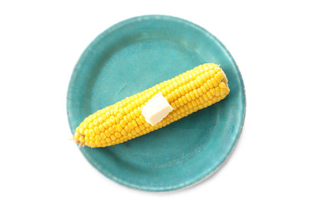 Plate of boiled corn cob with butter on white backgroundの写真素材