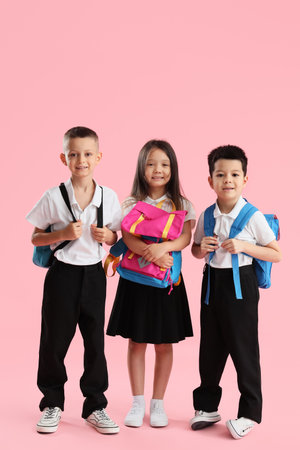 Little school children with backpacks on pink backgroundの写真素材