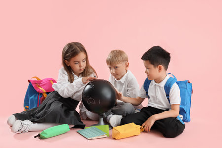 Little school children with globe on pink backgroundの写真素材